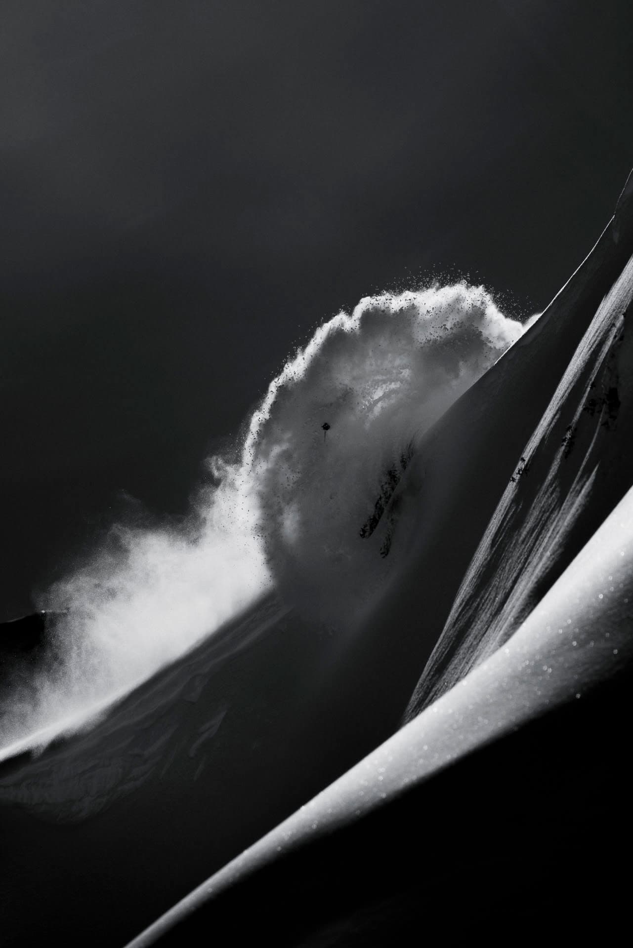 Skier descending a powder spine in black and white