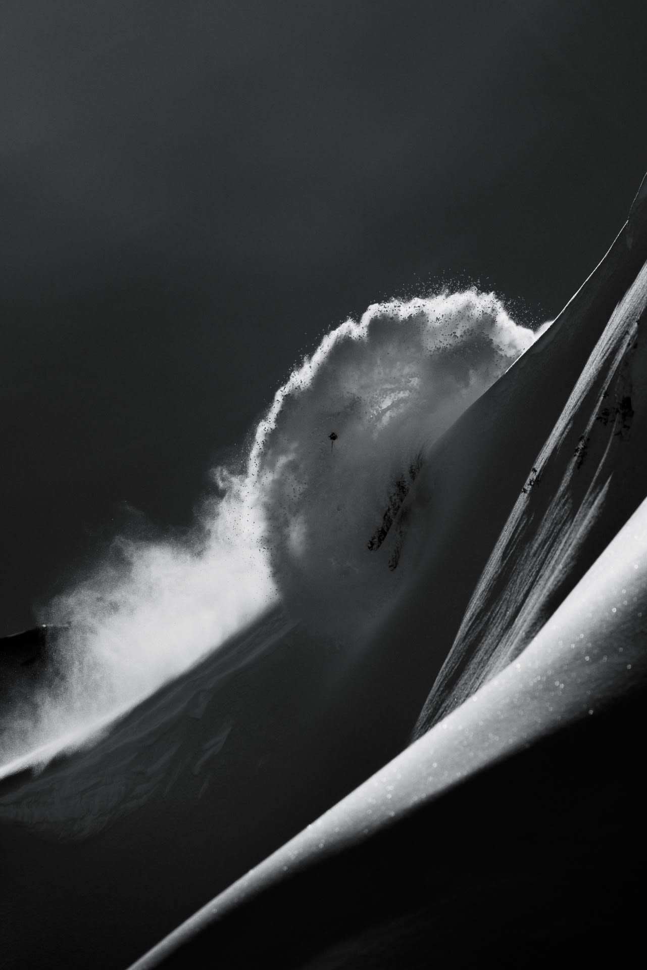 Skier descending a powder spine in black and white